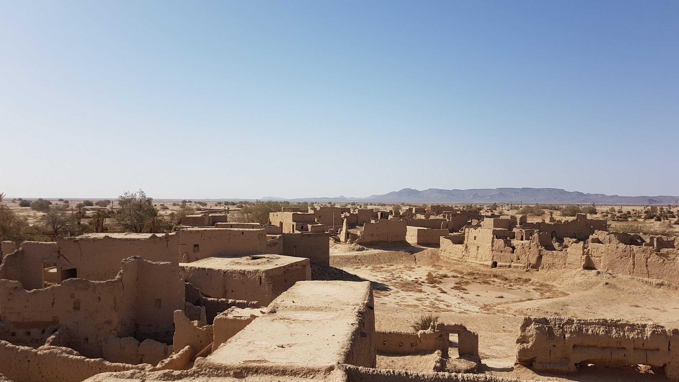 Abandoned mudbrick village seen from the rooftops, desert and distant hills beyond